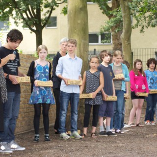 Schülerinnen und Schüler der Löcknitz Grundschule beschriften jedes Jahr Denk-Steine mit den Namen ehemaliger jüdischer Mitbürger und fügen diese in einer feierlichen Zeremonie in eine beständig wachsende Gedenkmauer ein.